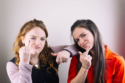 Portrait of friends gesturing while standing against white background