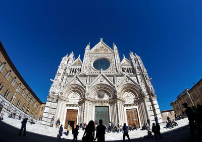 Group of people in front of building against blue sky