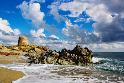 Rock formations on shore against sky