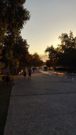 Silhouette people walking on road against sky during sunset