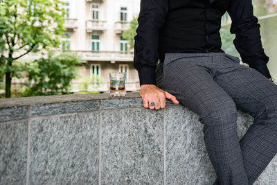 Low section of man sitting on retaining wall