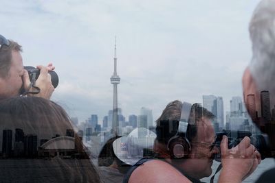 Portrait of man photographing with city in background