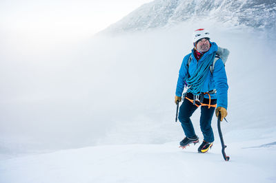 Full length of man with umbrella on snowy mountain