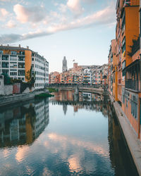 Buildings by river against sky in city