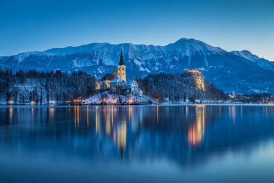 Bled castle in lake by mountains at dusk