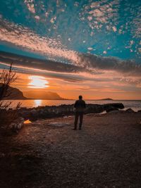 Man standing on beach against sky during sunset
