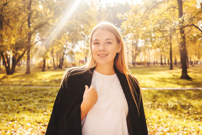 Portrait of smiling young woman standing against trees