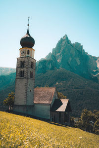 Traditional building by mountains against clear sky