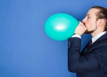 Midsection of man with balloons against blue sky