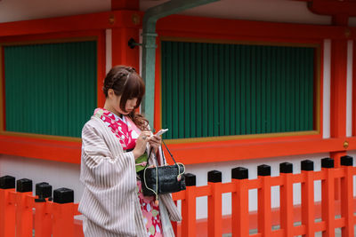 Full length of woman standing against red wall