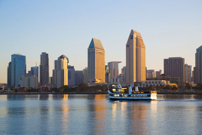 Sea by modern buildings in city against sky