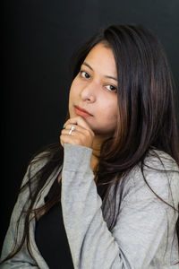 Close-up portrait of young woman against black background