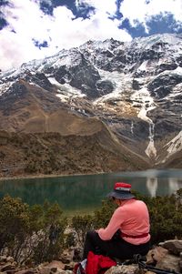 Rear view of woman sitting on snowcapped mountains against sky