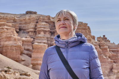 Portrait of senior caucasian woman on background of rocks of charyn canyon, kazakhstan.