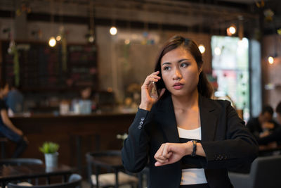 Businesswoman talking on smart phone at cafe