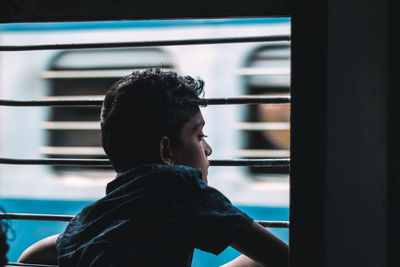 Portrait of young man looking through window