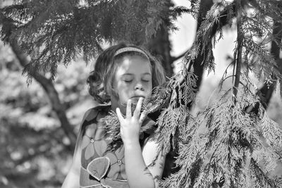 Girl with eyes closed standing by leaves