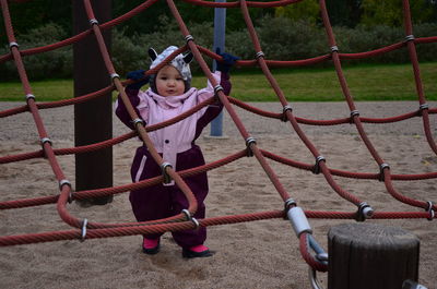 Portrait of baby girl holding rope at playground