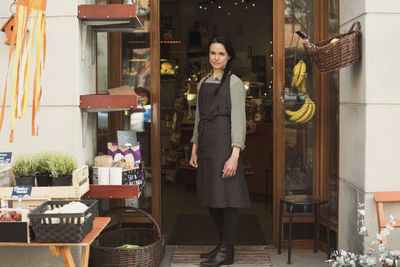 Full length of owner standing at store entrance