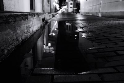 Reflection of illuminated building in puddle at night