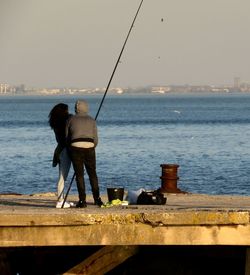 Rear view of couple fishing on shore