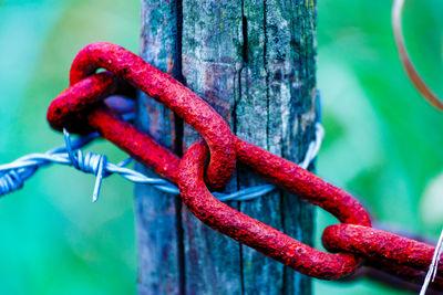 Close-up of rusty metal tied up on wooden fence