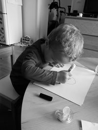 High angle view of boy drawing on paper at home