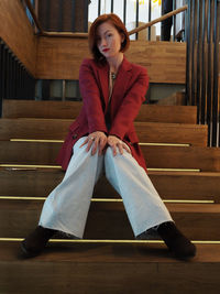 Portrait of young woman sitting on staircase at home