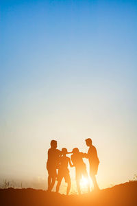 Silhouette people playing on field against sky during sunset