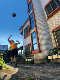 Man playing with ball against building in city