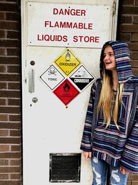 Portrait of young woman with text on brick wall