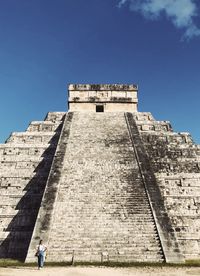 Low angle view of woman walking to mayan pyramid  building against sky