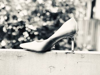 Close-up of high heels on retaining wall outdoors