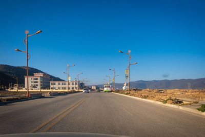 Street by road against blue sky