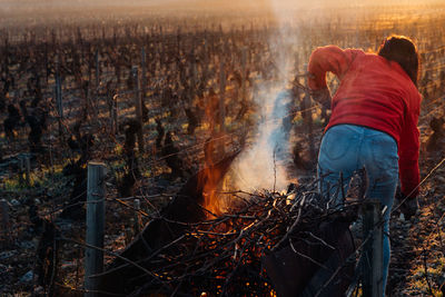 Rear view of woman standing by bonfire