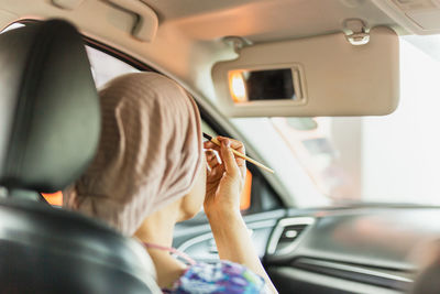 Woman enjoys while makeup herself in the car