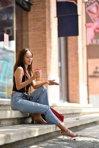 Full length of young woman drinking water