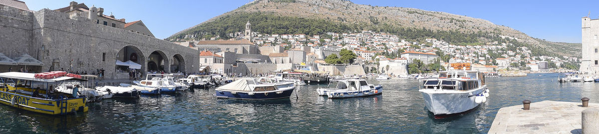 Boats moored in city against clear sky