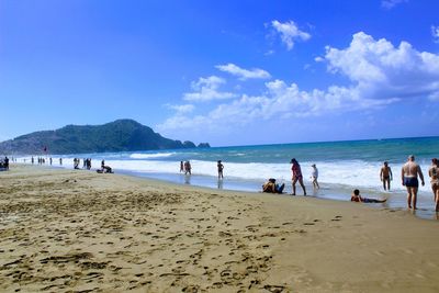 People on beach against blue sky