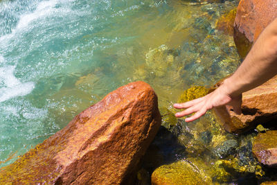 Low section of man on rock by water