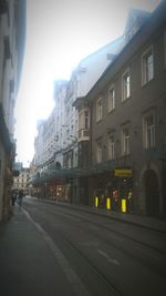 Railroad tracks by buildings in city against sky