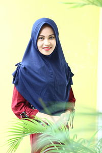 Portrait of smiling young woman standing against wall