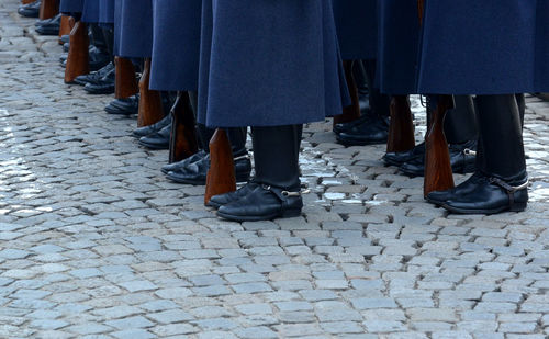 Low section of soldiers standing with guns on footpath