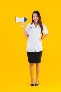 Portrait of smiling woman standing against yellow background