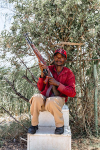 Full length of man sitting by tree