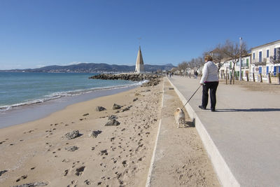 Rear view of woman on beach against clear sky