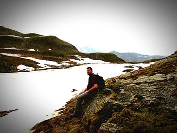 Rear view of man sitting on mountain