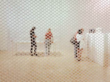 Close-up of figurine people seen through fence