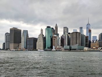 Modern cityscape by sea against sky