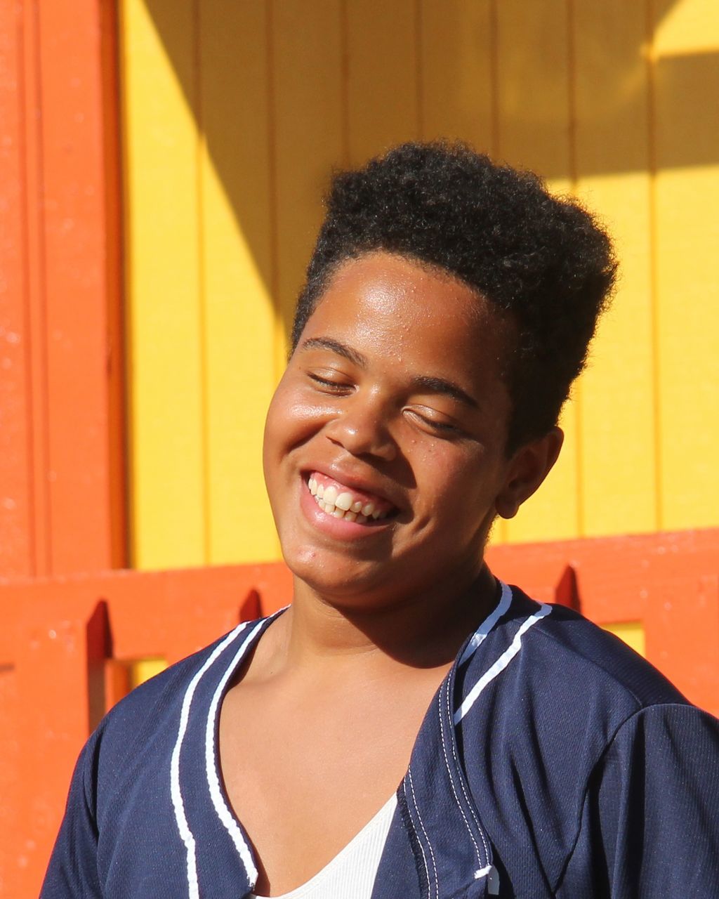 CLOSE-UP PORTRAIT OF SMILING YOUNG MAN AGAINST WALL